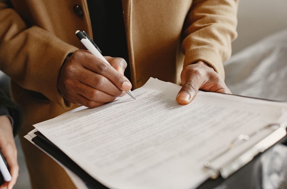 A Jay Ess Unity field executive completing an observation sheet on a clipboard during a verification visit.